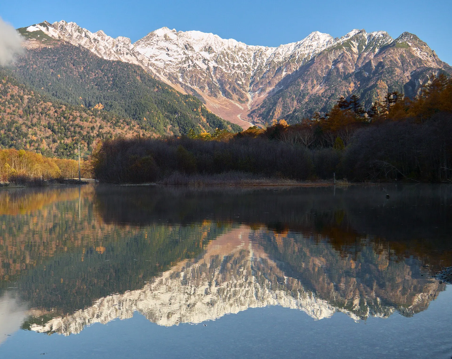 紅葉した森と穂高連峰が水面に映る大正池